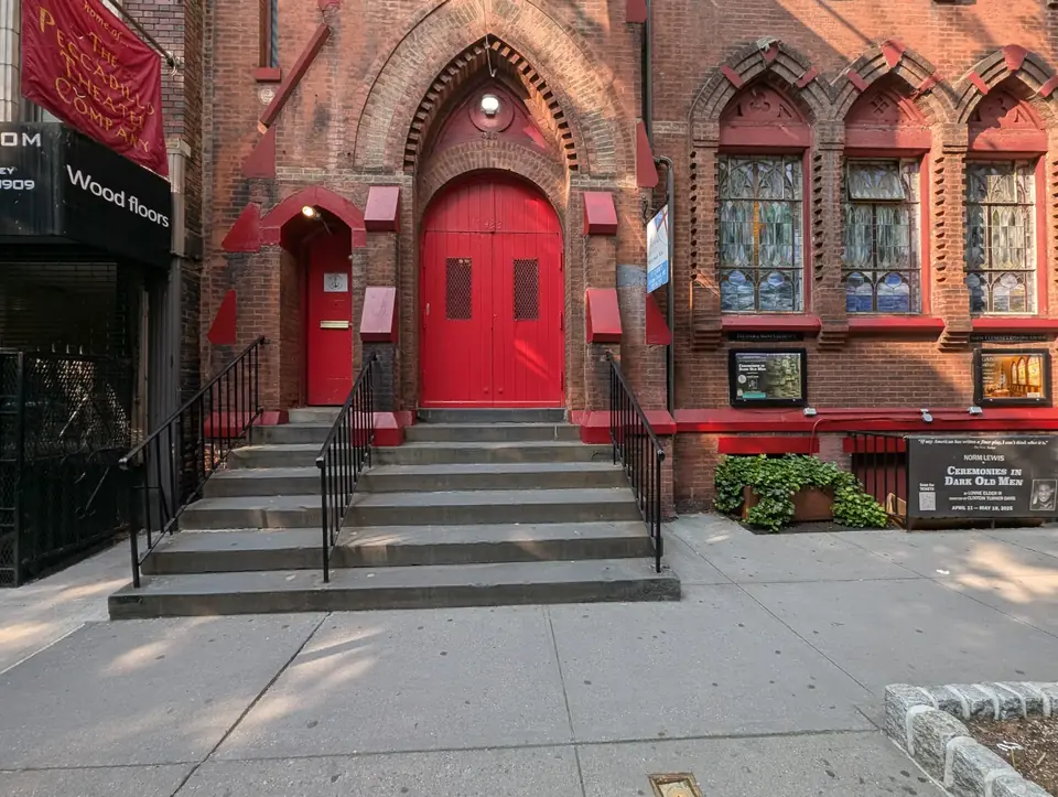 The front of St. Clement’s on West 46th Street: the steps up to the red doors under the brick arch, and the stained-glass windows