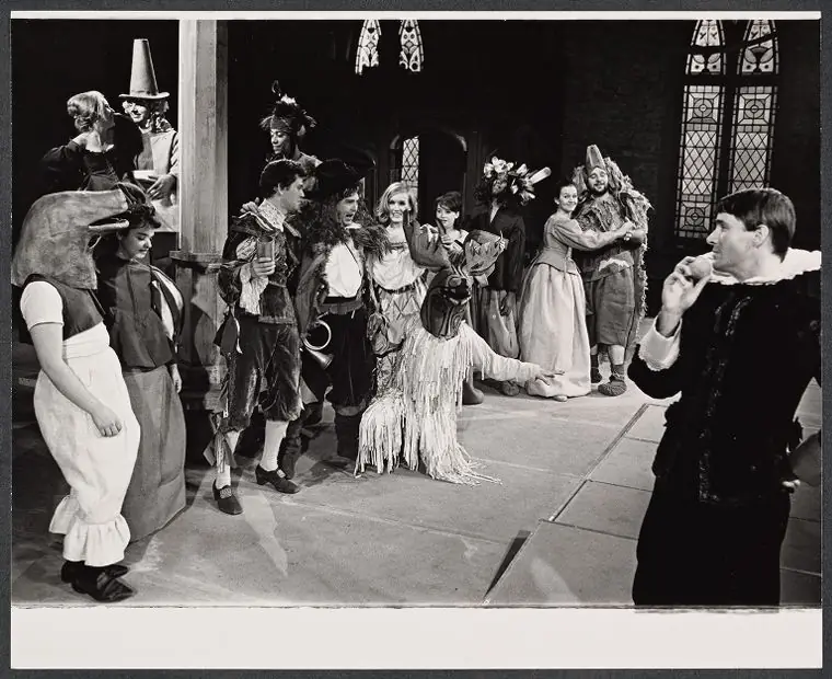 The Old Glory company in costume and masks on the stage, with tall Gothic windows behind them