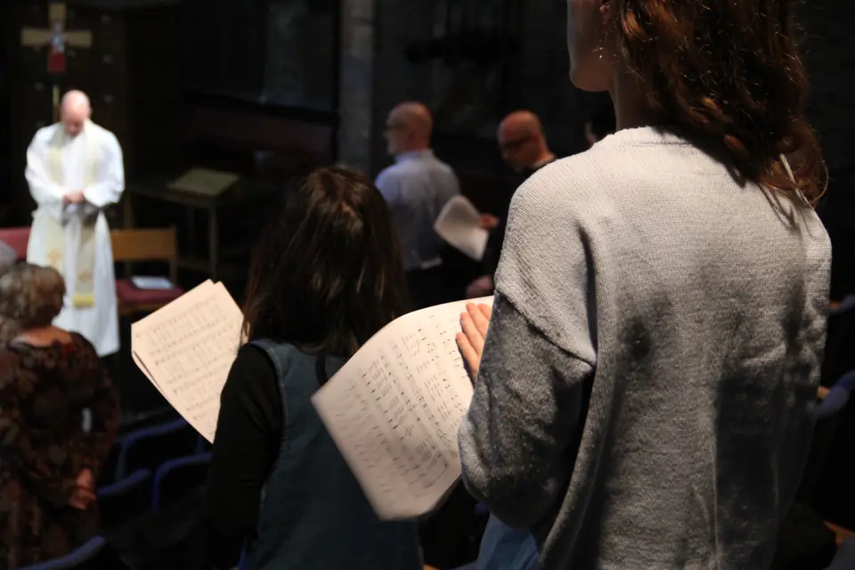 Sunday at St. Clement’s: the congregation standing with their service sheets, the priest at the altar beyond