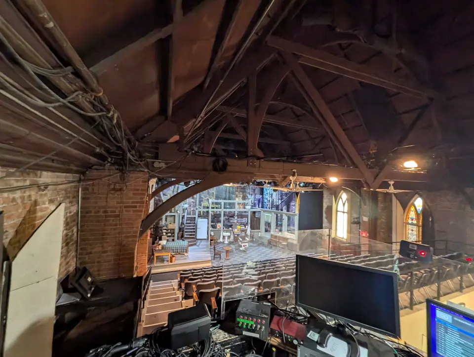 The view from the lighting booth, house left, past the console and over the seats to a set on the stage